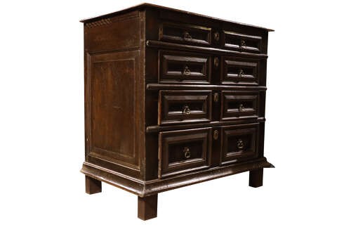 A dark oak Charles II chest of drawers featuring geometric panelled fronts, brass teardrop handles, and keyhole escutcheons. View II