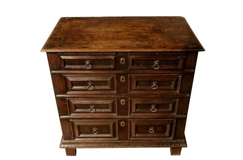 A dark oak Charles II chest of drawers featuring geometric panelled fronts, brass teardrop handles, and keyhole escutcheons. View III