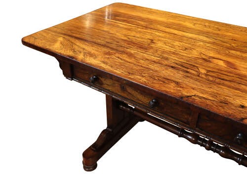 A William IV rosewood library table featuring a rectangular top, two frieze drawers with turned wooden knobs, trestle end supports, and a central turned stretcher. View VI