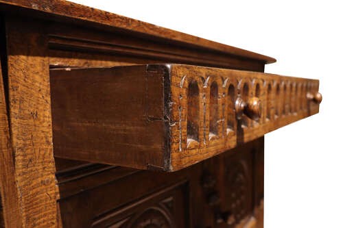 A warm brown carved oak side cabinet featuring drop-leaf top extensions, arcaded carved cupboard doors, turned legs, and a lower pot board shelf. View VII