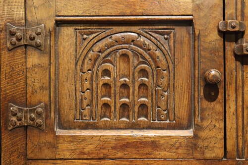 A warm brown carved oak side cabinet featuring drop-leaf top extensions, arcaded carved cupboard doors, turned legs, and a lower pot board shelf. View VIII