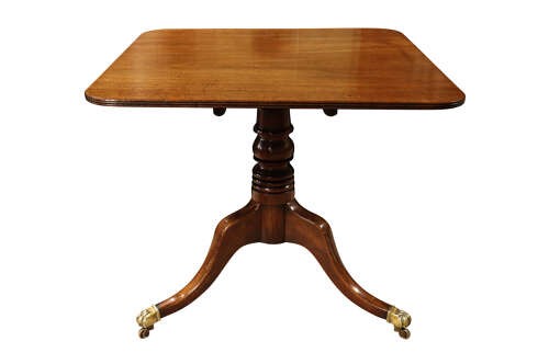 A George III mahogany pedestal supper table featuring a rounded square tilt top, turned central column, and splayed legs with brass paw castors. View II