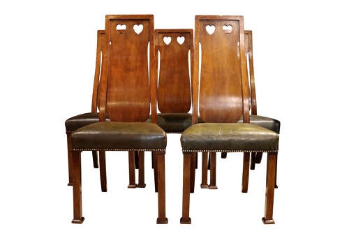 A set of six Arts and Crafts solid oak dining chairs featuring tall backsplats with heart-shaped cutouts and green leather seats with brass studding. View IV