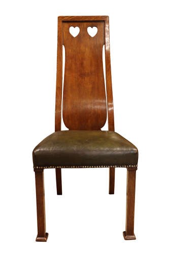 A set of six Arts and Crafts solid oak dining chairs featuring tall backsplats with heart-shaped cutouts and green leather seats with brass studding. View V