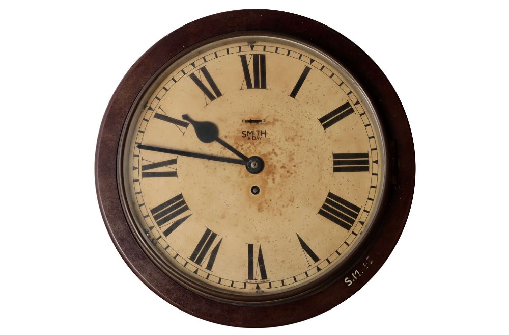 A circular early twentieth-century Bakelite wall clock with a cream dial, black Roman numerals, and black spatulate hands.