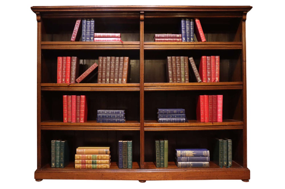 A wide Edwardian mahogany double-width open bookcase featuring adjustable shelves, a moulded cornice, and a sturdy plinth base.