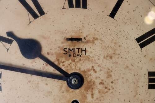 A circular early twentieth-century Bakelite wall clock with a cream dial, black Roman numerals, and black spatulate hands. View IV