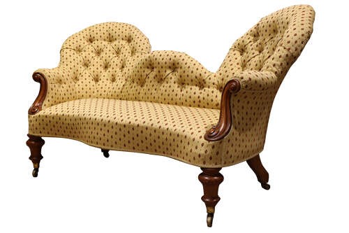 A Victorian mahogany double-ended settee featuring deep-buttoned patterned yellow upholstery, carved scroll arms, and turned legs with brass castors. View III