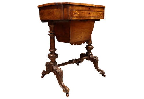 A Victorian burr walnut sewing table featuring intricate marquetry inlay on top, turned legs with carved feet, and a drop-down sewing well beneath a single drawer. View VI