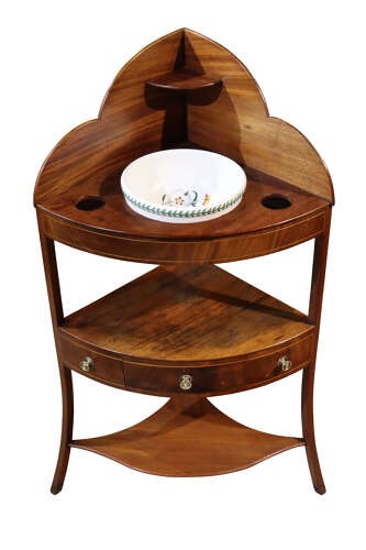 A George IV mahogany corner washstand featuring a stepped splashback with a corner shelf, stringing inlay, curved drawers, and splayed legs. View II