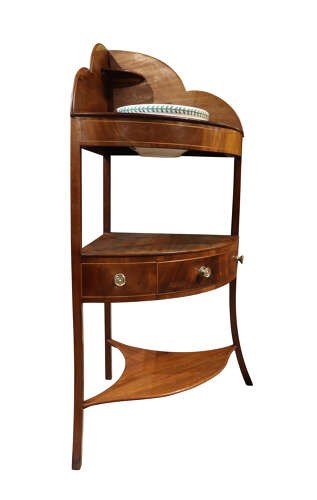 A George IV mahogany corner washstand featuring a stepped splashback with a corner shelf, stringing inlay, curved drawers, and splayed legs. View III