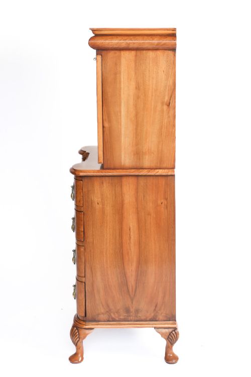 fig 1. A Queen Anne style burr walnut escritoire featuring a fall-front writing upper cabinet atop a chest of drawers with brass drop handles and carved cabriole legs.