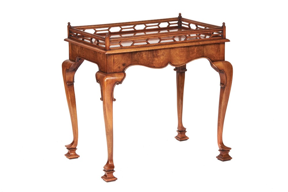 A Georgian Revival walnut silver table featuring a pierced fretwork gallery top, shaped apron, and carved cabriole legs terminating in pad feet.