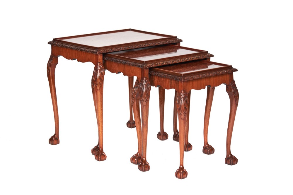 A set of three graduated burr walnut nesting tables featuring carved cabriole legs, carved knee detail, ball and claw feet, and moulded rim table tops.