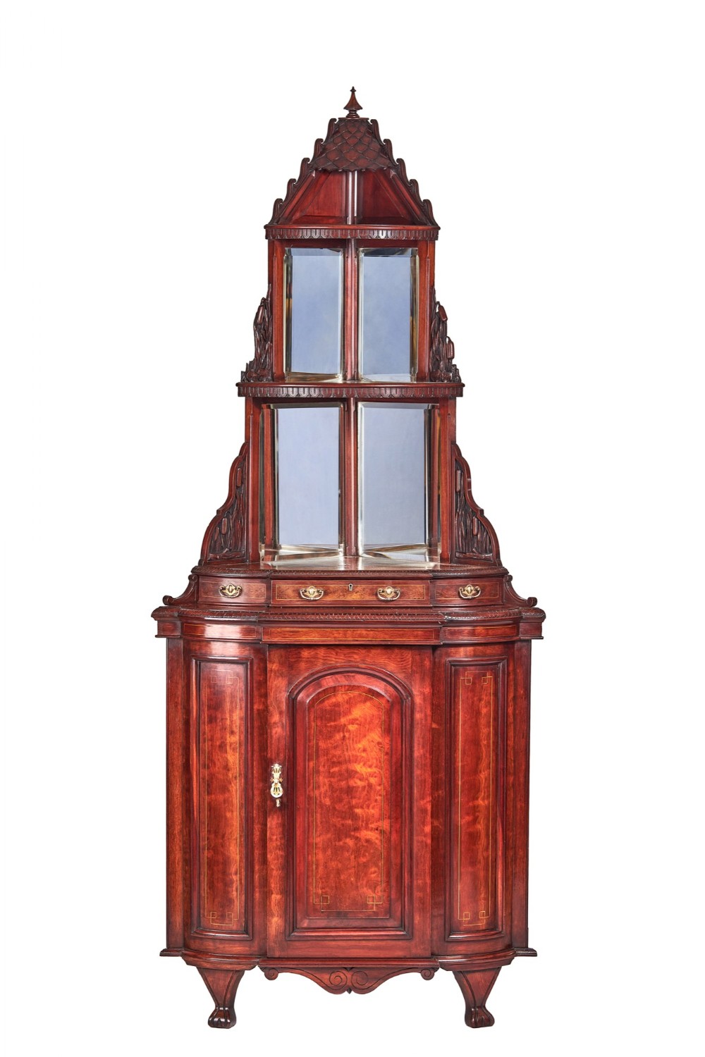 A tall Victorian walnut corner cabinet featuring a tiered mirrored upper section topped with a carved finial above a base cupboard with panelled wood veneer.