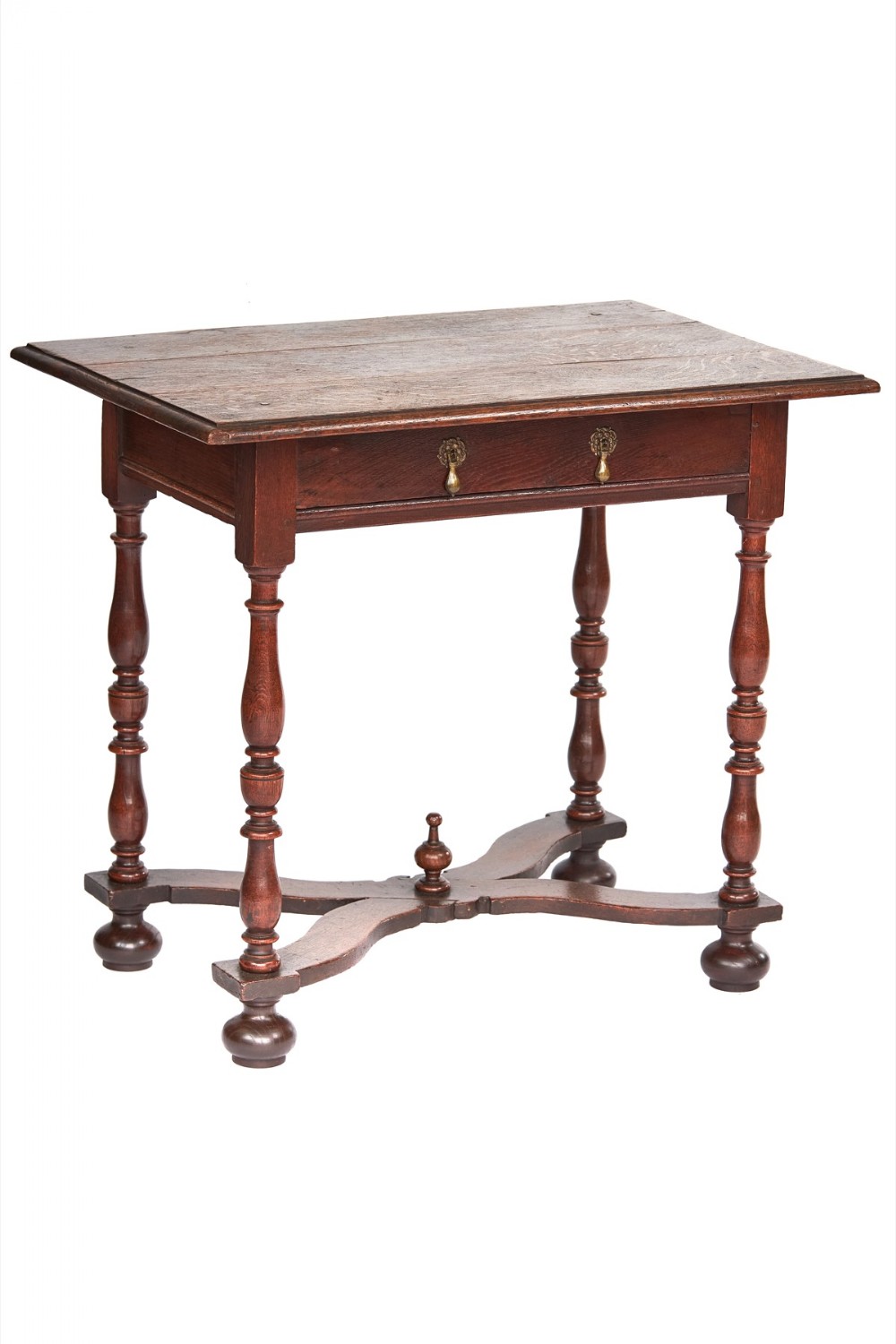 An antique dark oak lowboy table featuring turned legs, a single drawer with brass handles, a central finial on an X-frame stretcher, and ball feet.