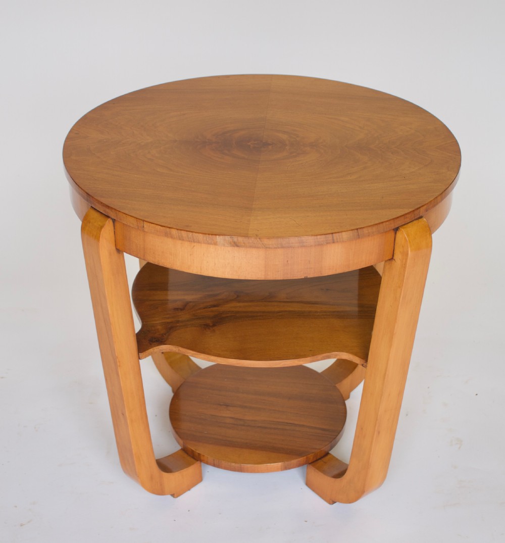 A circular Art Deco walnut side table featuring three tiers and curved leg supports.
