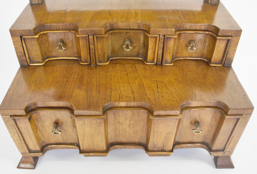 An antique Queen Anne Revival walnut dressing mirror featuring an arched swivelling mirror plate above a two-tiered serpentine drawer base. View V