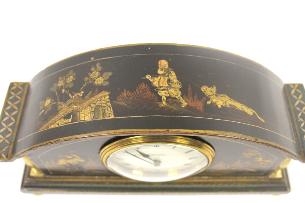 A 1920s arched black lacquered mantel clock decorated with gilded chinoiserie scenes, turned brass columns, and a cream dial with Roman numerals. View II