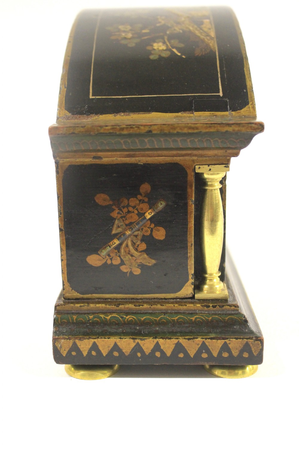 A 1920s arched black lacquered mantel clock decorated with gilded chinoiserie scenes, turned brass columns, and a cream dial with Roman numerals. View V