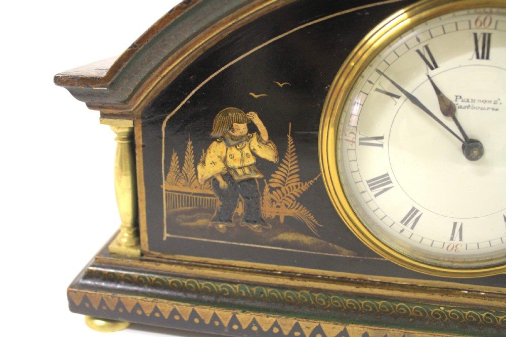 A 1920s arched black lacquered mantel clock decorated with gilded chinoiserie scenes, turned brass columns, and a cream dial with Roman numerals. View VI
