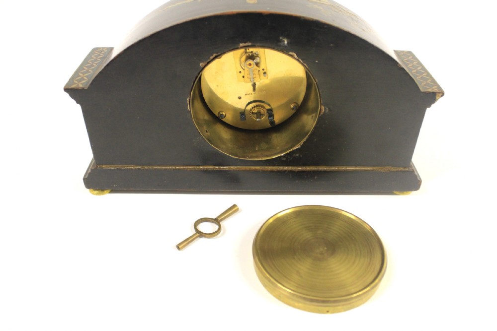 A 1920s arched black lacquered mantel clock decorated with gilded chinoiserie scenes, turned brass columns, and a cream dial with Roman numerals. View VII