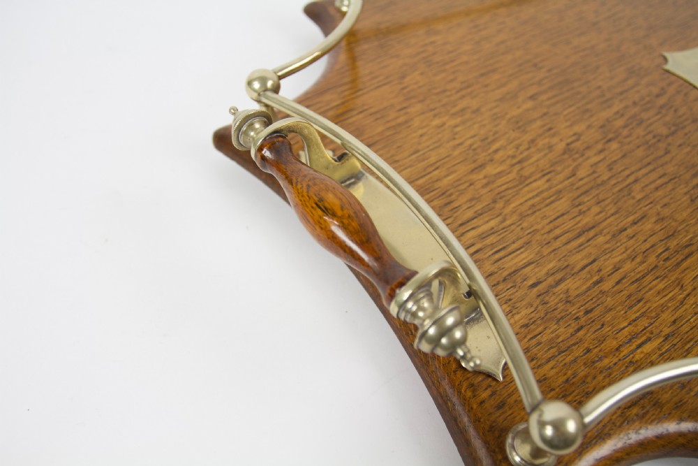 An antique shaped oak serving tray featuring a metal gallery rail, side handles with turned wooden grips, and a central metal cartouche. View II