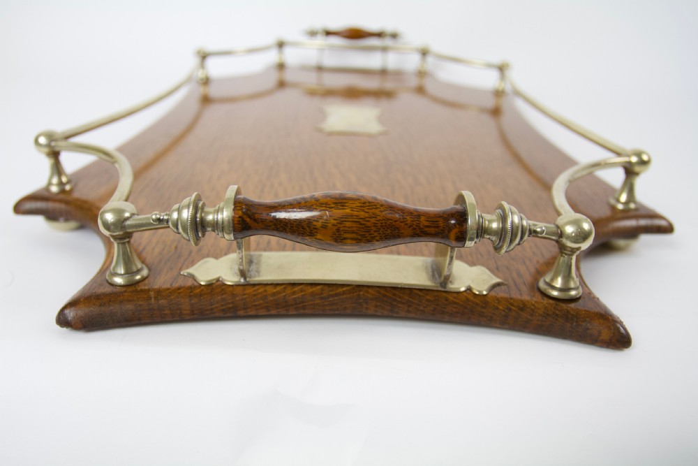 An antique shaped oak serving tray featuring a metal gallery rail, side handles with turned wooden grips, and a central metal cartouche. View III