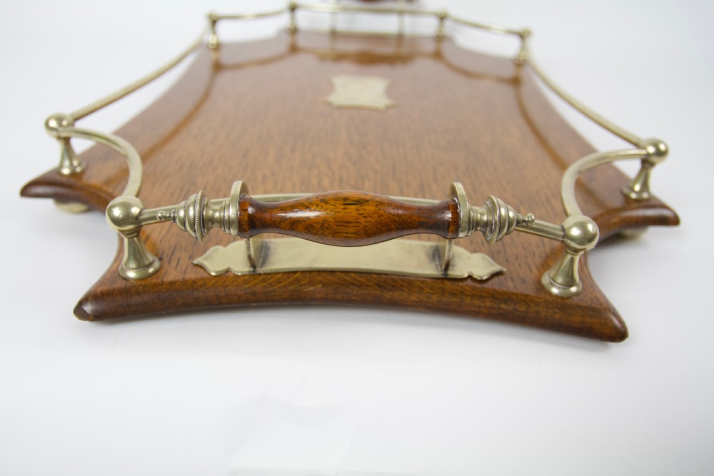 An antique shaped oak serving tray featuring a metal gallery rail, side handles with turned wooden grips, and a central metal cartouche. View IV