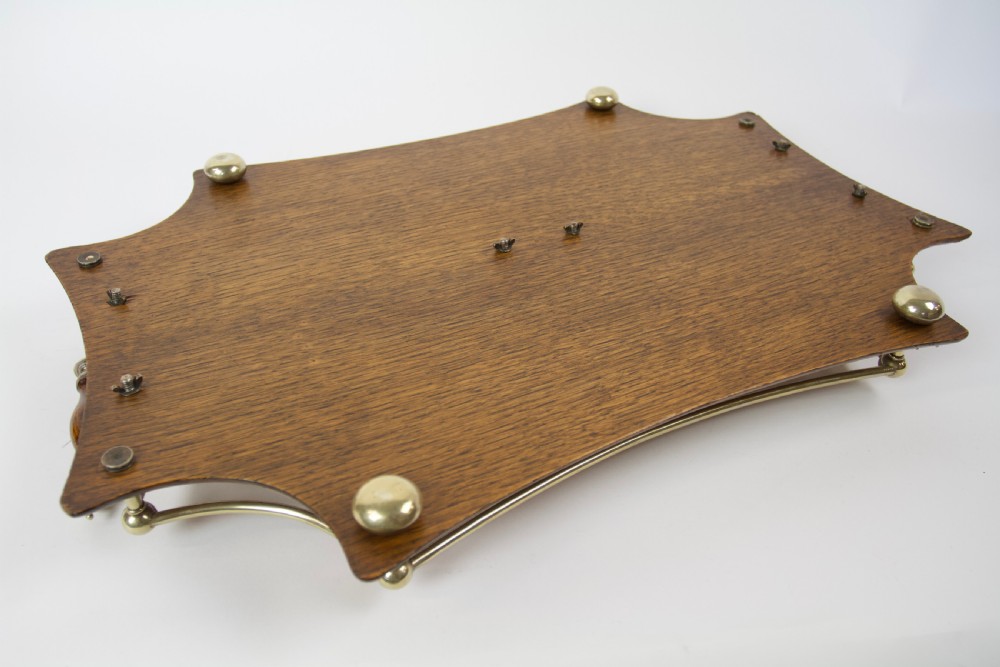 An antique shaped oak serving tray featuring a metal gallery rail, side handles with turned wooden grips, and a central metal cartouche. View V