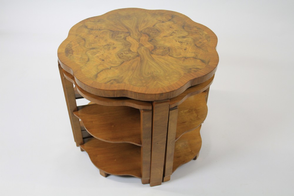 An Art Deco burr walnut nest of tables featuring a cloud-shaped top and four fitted segment side tables underneath.