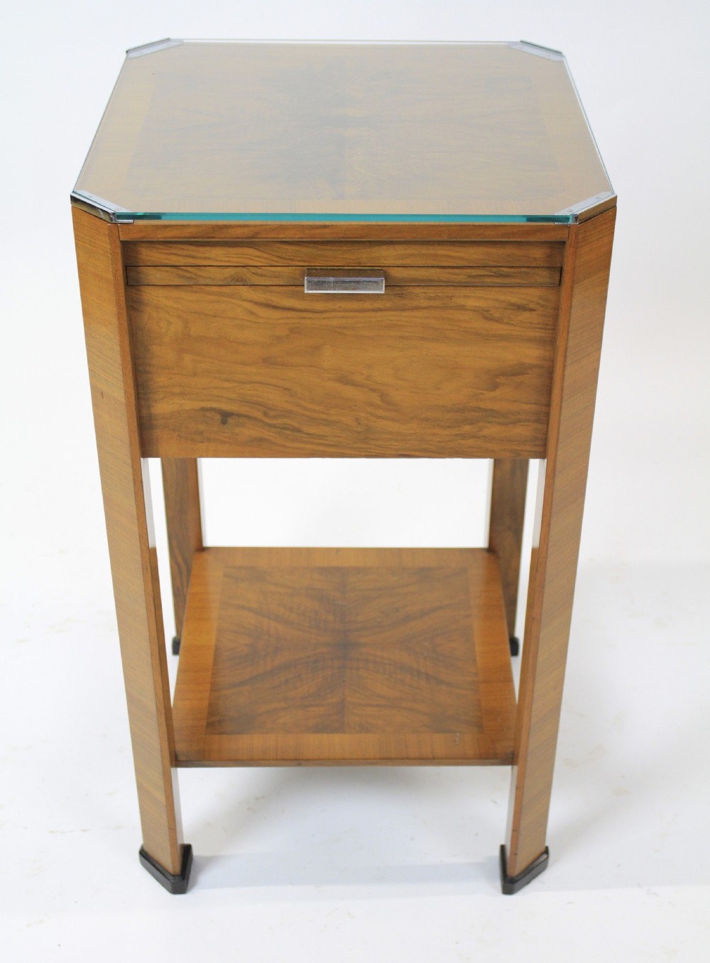 An Art Deco two-tier walnut side table featuring a square glass top, chrome corner grips, a lower shelf, and four pull-out maple slides extending from each side. View VI