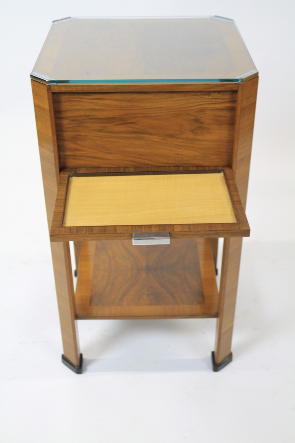 An Art Deco two-tier walnut side table featuring a square glass top, chrome corner grips, a lower shelf, and four pull-out maple slides extending from each side. View IX