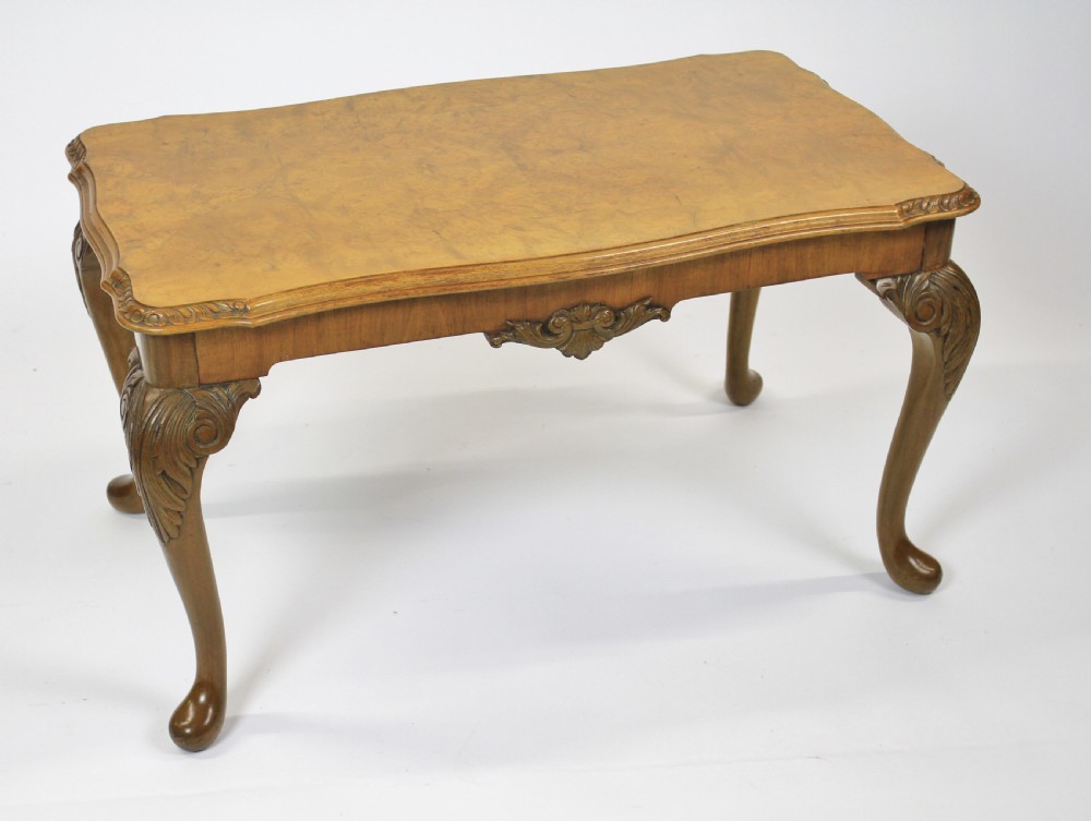 A low rectangular burr walnut coffee table featuring a serpentine edge, carved central shell motif, and four carved cabriole legs. View II
