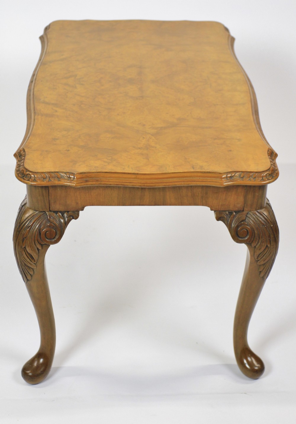A low rectangular burr walnut coffee table featuring a serpentine edge, carved central shell motif, and four carved cabriole legs. View III