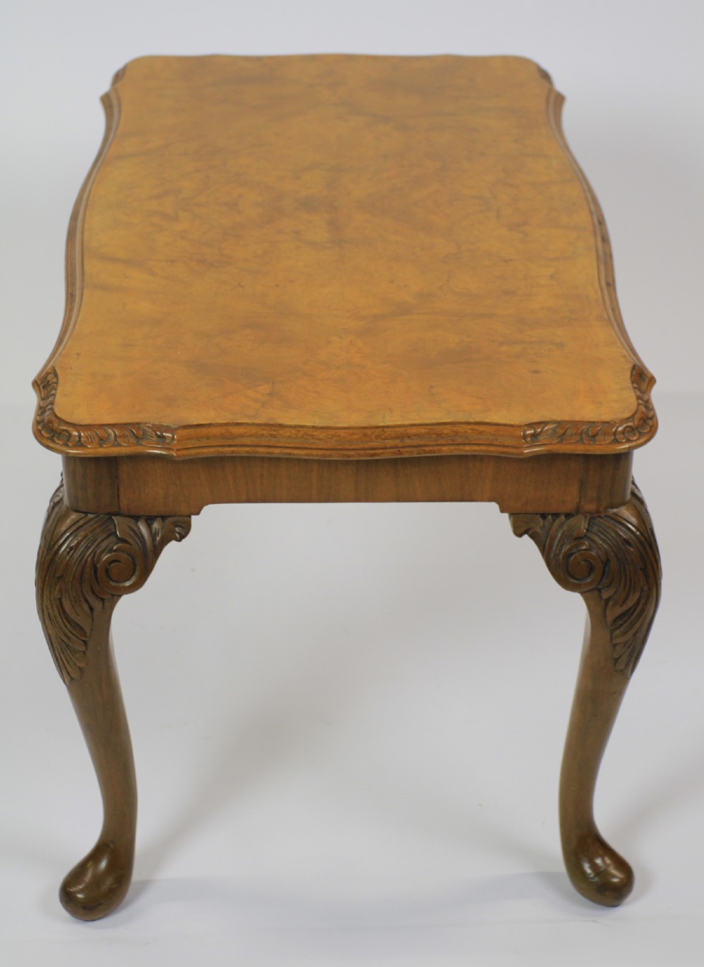 A low rectangular burr walnut coffee table featuring a serpentine edge, carved central shell motif, and four carved cabriole legs. View IV