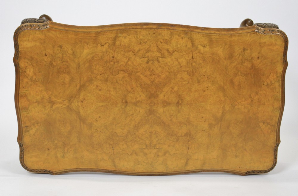 A low rectangular burr walnut coffee table featuring a serpentine edge, carved central shell motif, and four carved cabriole legs. View V