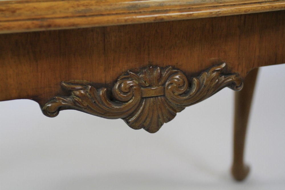 A low rectangular burr walnut coffee table featuring a serpentine edge, carved central shell motif, and four carved cabriole legs. View VII