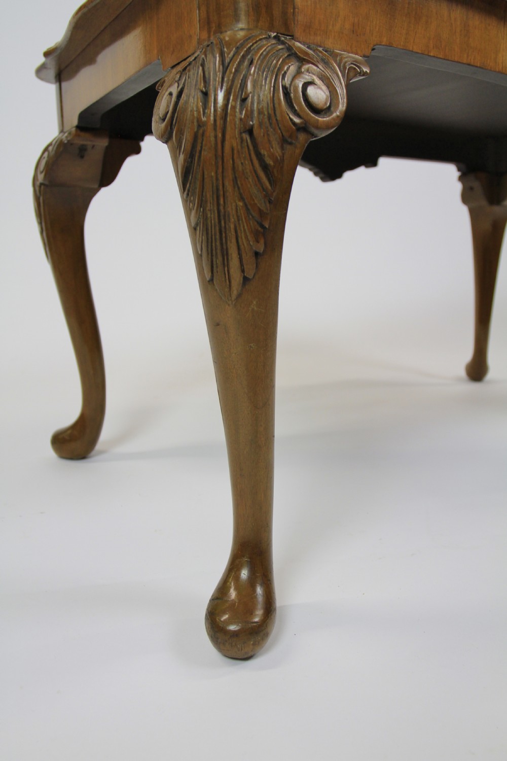A low rectangular burr walnut coffee table featuring a serpentine edge, carved central shell motif, and four carved cabriole legs. View VIII