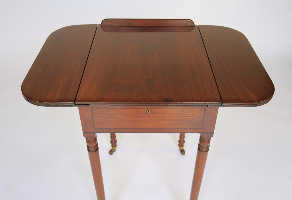 A Regency mahogany writing table with an adjustable ratchet top, side drop flap, internal fitted pen compartment, slim turned legs, and brass castors. View XI