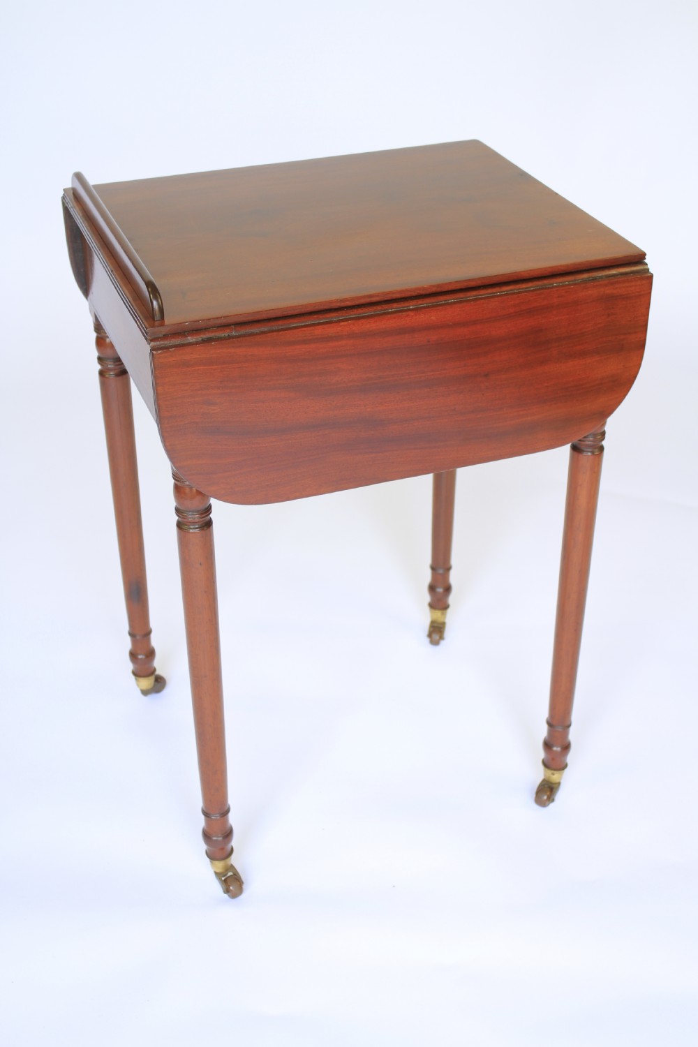 A Regency mahogany writing table with an adjustable ratchet top, side drop flap, internal fitted pen compartment, slim turned legs, and brass castors. View III