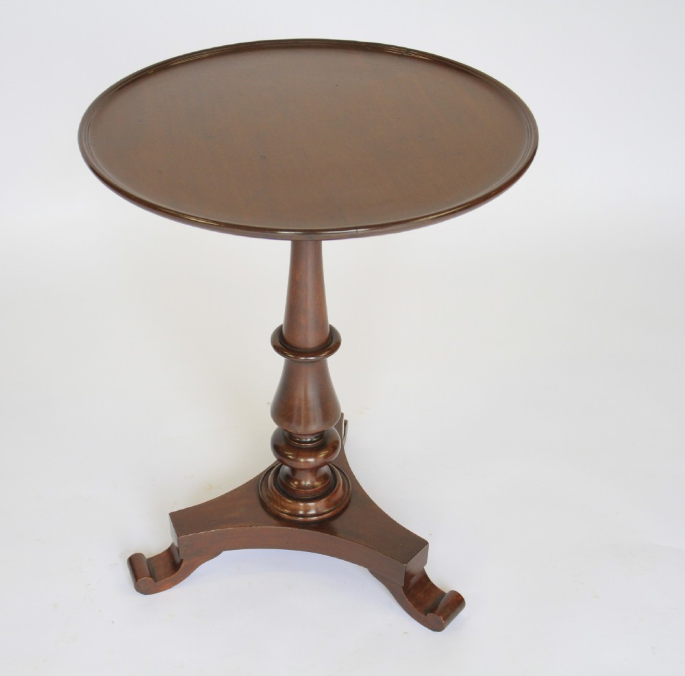 A William IV dark mahogany tilt-top table featuring a raised moulded edge rim, a turned central pedestal stem, and a tri-form platform base on scroll feet. View III