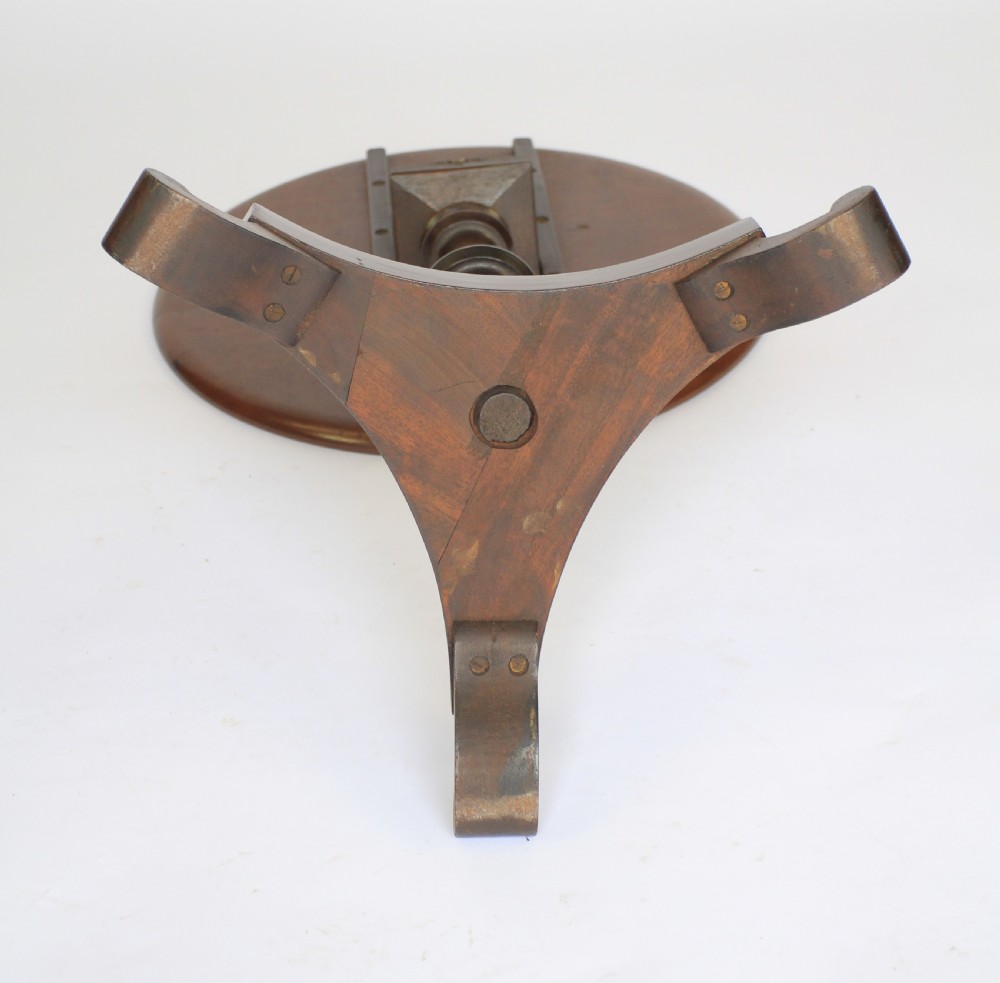 A William IV dark mahogany tilt-top table featuring a raised moulded edge rim, a turned central pedestal stem, and a tri-form platform base on scroll feet. View V