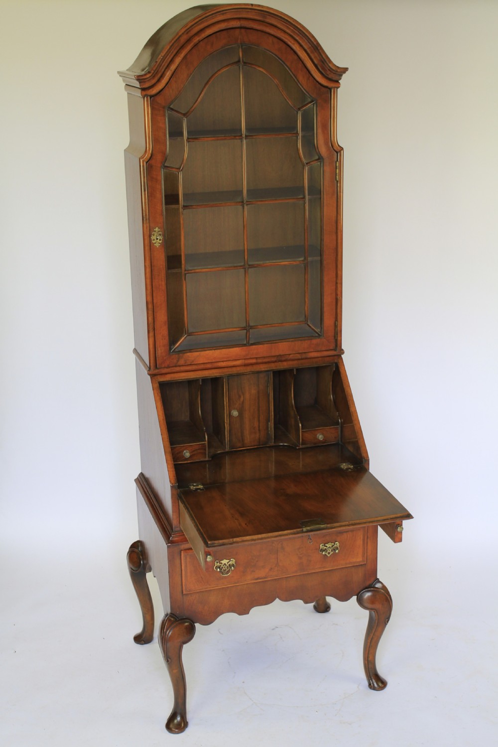 A tall Queen Anne Revival walnut bureau bookcase with an arched glazed upper door, slant-front writing slope, two drawers, and cabriole legs. View III