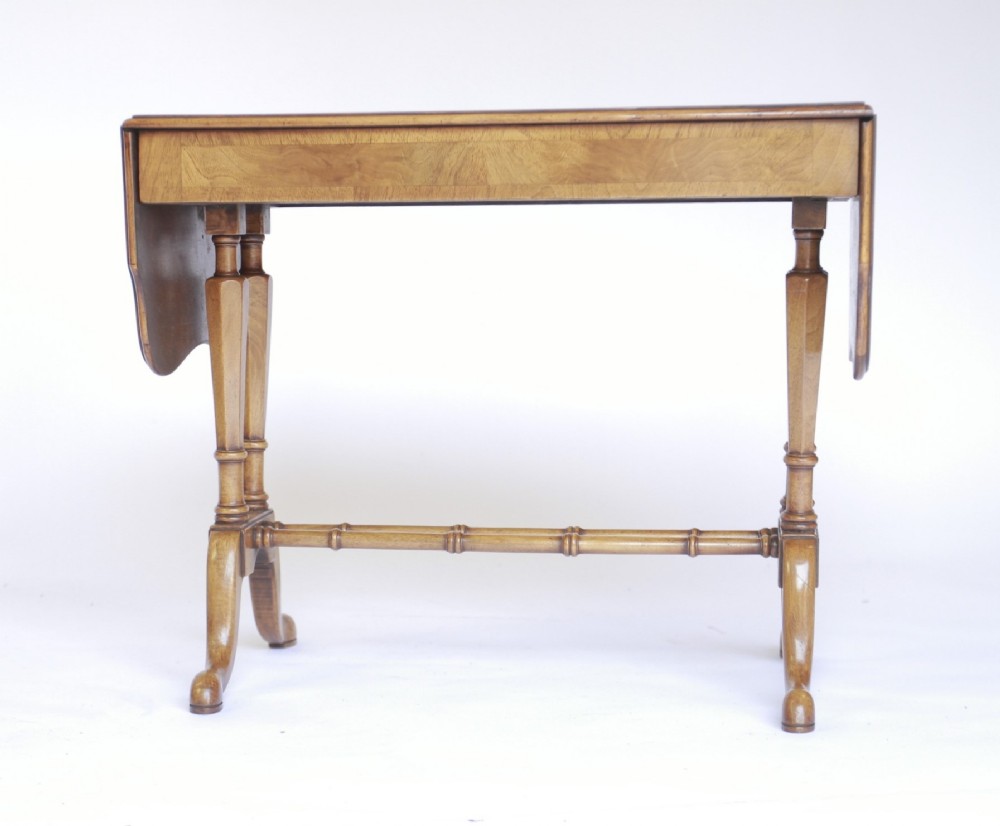 A 1930s walnut drop-leaf coffee table featuring turned supports, pad feet, and a central turned stretcher.
