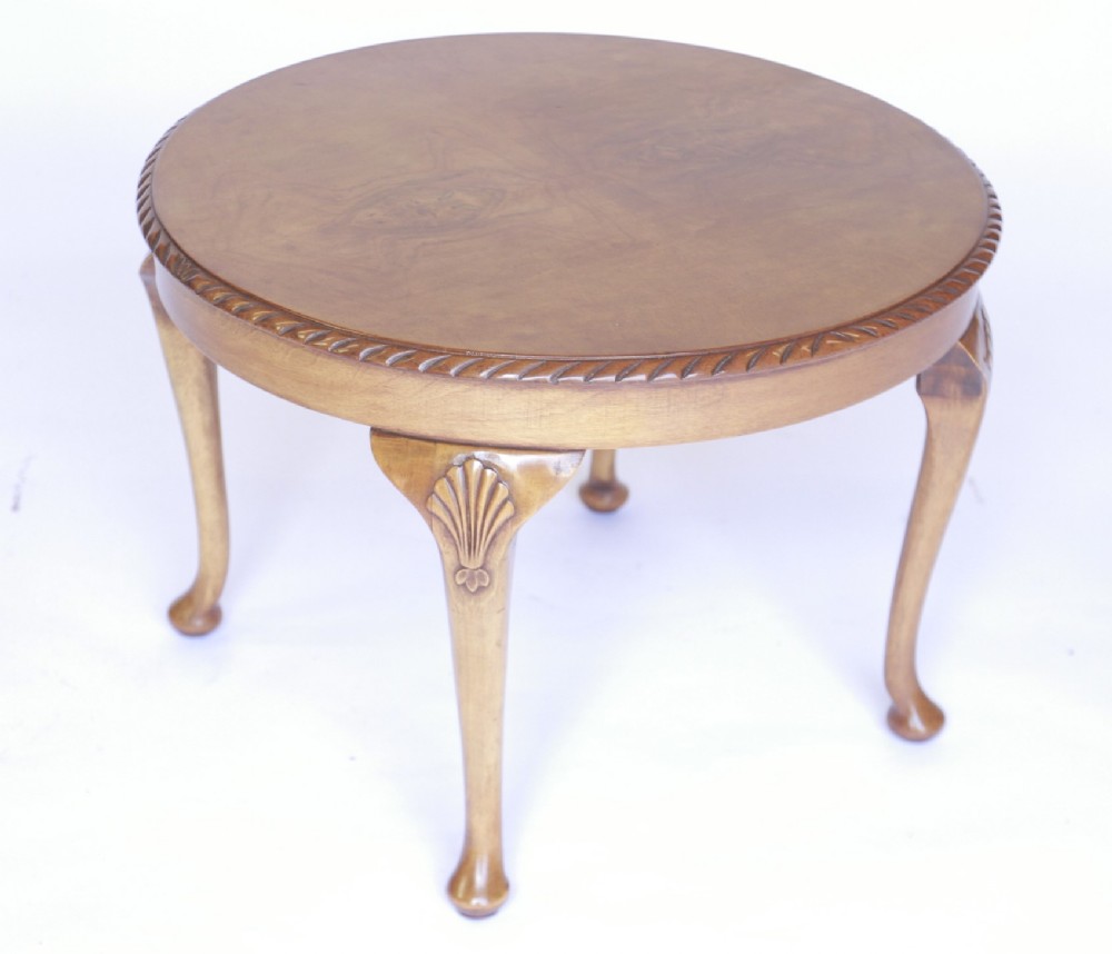 A circular 1930s walnut coffee table featuring carved shell knee motifs, cabriole legs ending in pad feet, and a carved rim border.