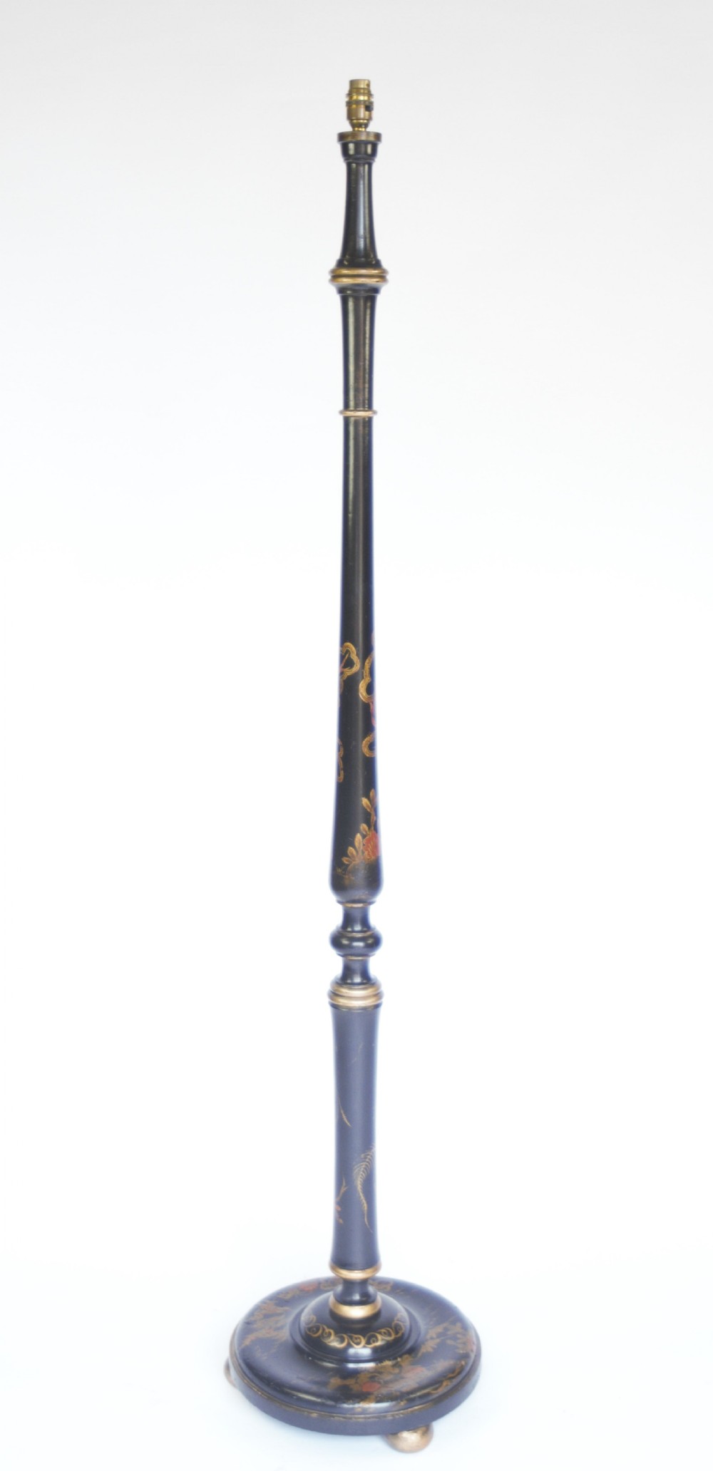 A tall black lacquered turned wooden standard lamp decorated with hand-painted gold floral Chinoiserie designs resting on a circular base.