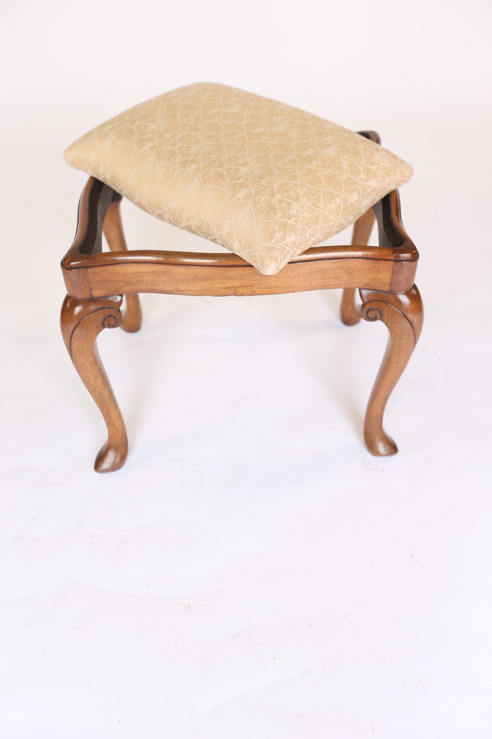 A 1930s Queen Anne style walnut dressing stool featuring carved cabriole legs and a cream patterned fabric seat. View VI