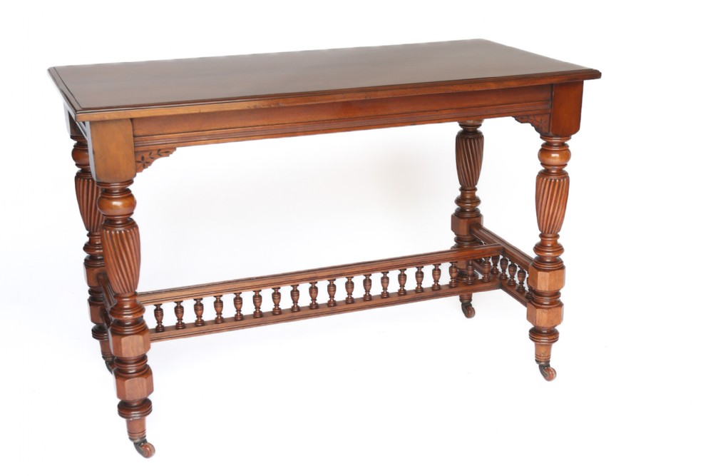 A late Victorian carved walnut centre table featuring a rectangular top, spiral-turned legs, a gallery stretcher with vertical spindles, and brass castors.
