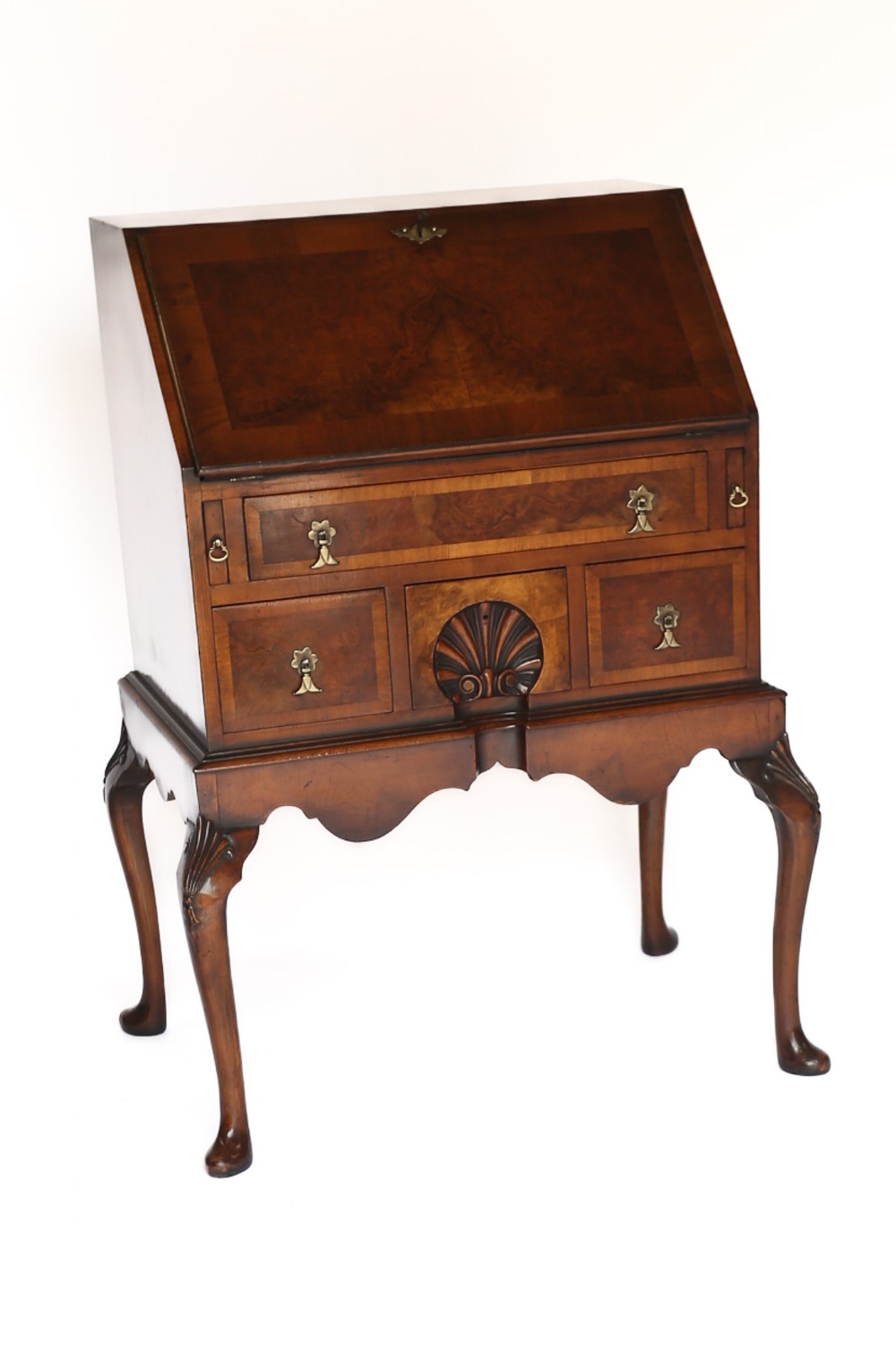 A Georgian style walnut slant-front bureau featuring a hinged writing flap, drawers with brass handles, carved shell details, and cabriole legs.